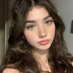 Woman with long wavy dark hair and green eyes looking at the camera
