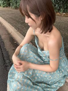 Woman with short hair in a floral dress sitting outdoors