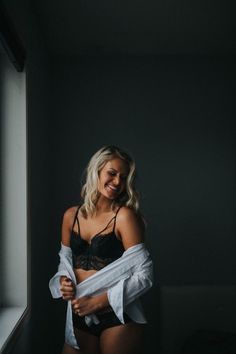 Blonde woman in black lingerie and a white shirt indoors