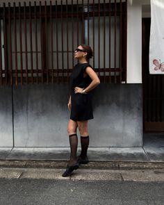 Woman in a black dress and knee-high socks standing on a street