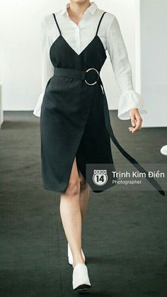 Woman in a black midi dress over a white shirt with ruffle cuffs