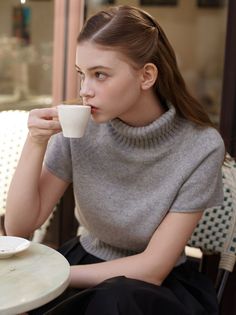 Woman with long hair drinking coffee at an outdoor cafe