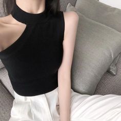 Person in a black cut-out top and white pants sitting on a couch