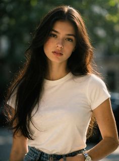 Woman with long dark hair wearing a white t-shirt and jeans outdoors