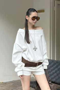 Woman in an off-shoulder top, white shorts, and sunglasses outdoors
