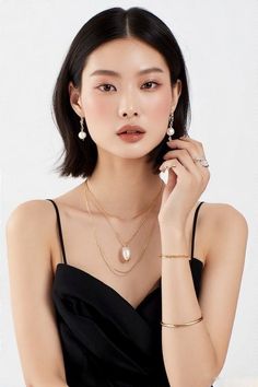 Woman with short black hair wearing pearl earrings and a layered necklace