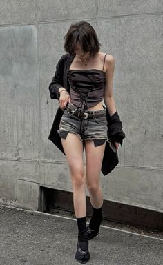 Woman with short hair wearing a corset top and distressed shorts outdoors