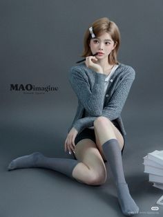 Woman with short hair and a grey cardigan sitting on a plain background