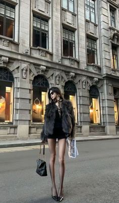 Woman in a fur coat and short dress standing on a city street