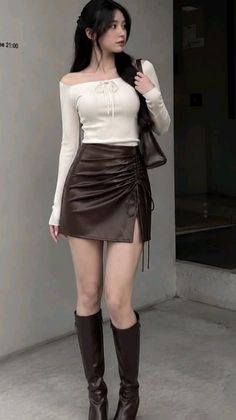 Woman with long dark hair wearing an off-shoulder top and brown mini skirt