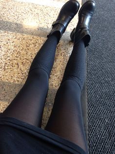 Person wearing black boots and tights, sitting indoors
