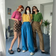 Three women in colorful polo shirts and casual outfits taking a mirror selfie