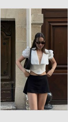 Woman in a white crop top and black mini skirt posing outdoors