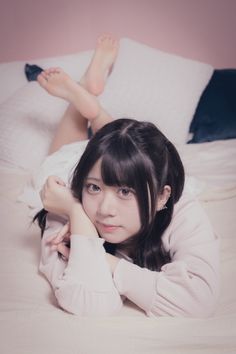 Woman with black pigtails lying on a bed with bare feet up