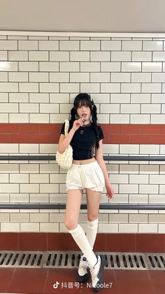 Woman with pigtails in a crop top and white shorts standing in a subway station