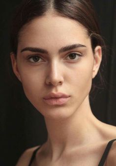 Close-up portrait of a woman with dark hair against a dark background