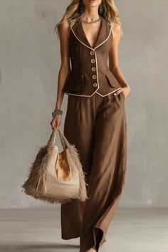 Woman in a brown sleeveless suit and wide-leg pants holding a fringed bag
