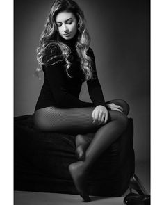 Woman in a black turtleneck and fishnet stockings sitting in a studio