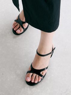 Person wearing black sandals and black pants on a light-colored floor