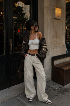 Woman in a brown leather jacket and cargo pants standing on a street
