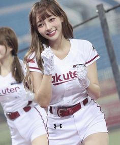 Cheerleader in a white uniform and sequin gloves smiling on a baseball field
