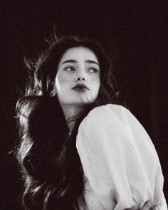 Woman with long dark hair in a white shirt, looking up and to the side