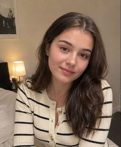 Woman with long brown hair wearing a striped cardigan indoors