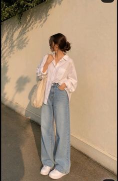 Woman in a white shirt and wide leg jeans with a tote bag outdoors