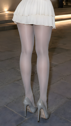 Person in a white skirt, white tights, and high heels standing outdoors at night