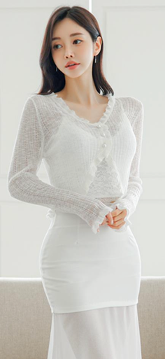 Woman in a white sheer top and skirt with ruffle trim, posing indoors