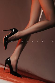 Woman's legs in black high heels with dramatic lighting and red accent
