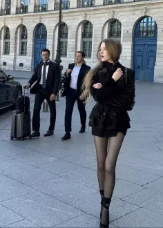 Woman in a black velvet jacket and mini skirt walking on a city street