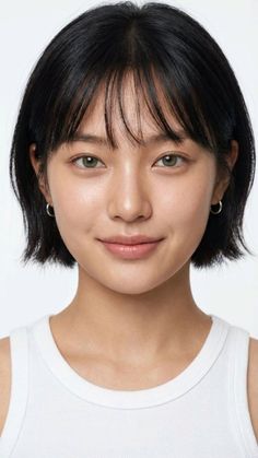 Woman with short black hair and green eyes wearing a white tank top