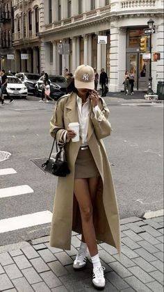 Woman in a trench coat and mini skirt walking on a city street