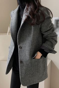 Person in a gray blazer and black turtleneck with long dark hair