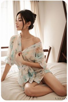 Woman in a floral robe sitting on a bed in a suggestive pose