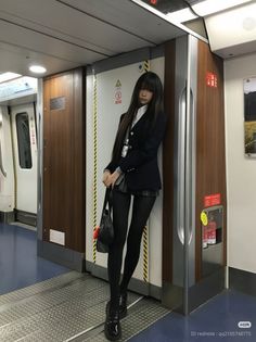 Person in a school uniform and black tights standing in a subway car