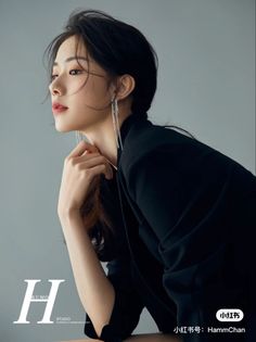 Woman with long black hair wearing a suit and long earrings in a studio portrait