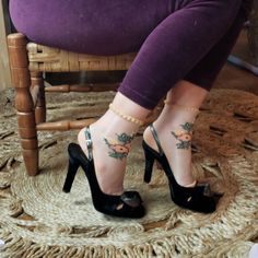 Person wearing black high heels and purple leggings, sitting on a chair