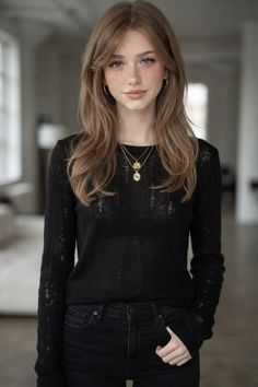 Woman with long hair and freckles wearing a black sheer top and layered necklaces