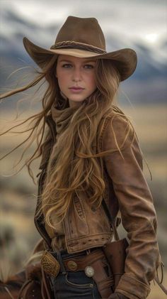 Woman in a cowboy hat and brown jacket with long flowing hair outdoors