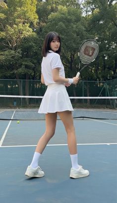 Woman in a white tennis outfit holding a racket on a tennis court
