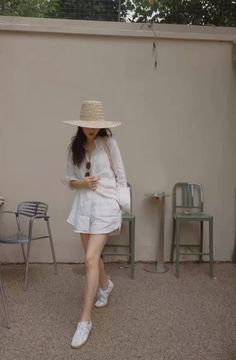 Woman in a straw hat, white shirt, and shorts outdoors