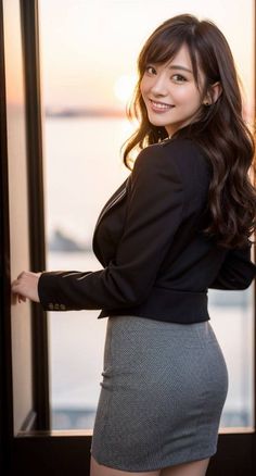 Woman in a black blazer and gray pencil skirt smiling at golden hour