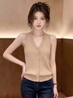 Woman with brown hair wearing a sleeveless top and jeans indoors