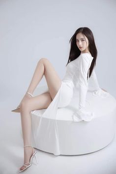 Woman in a white dress and high heels posing in a studio