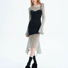 Woman in a black dress with a sheer long-sleeved top in a studio