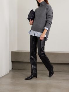 Woman in a gray turtleneck sweater, striped shirt, and black leather pants