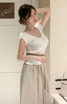 Woman with an updo wearing a white top and long skirt indoors