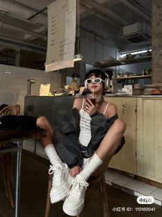 Person with short hair wearing sunglasses and headphones in a cafe